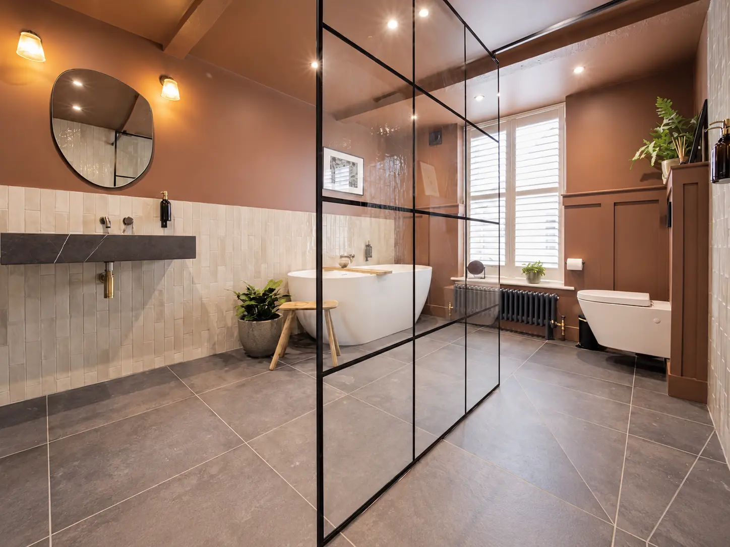 Bathroom with freestanding bath, black-framed wet room screen and wall panelling
