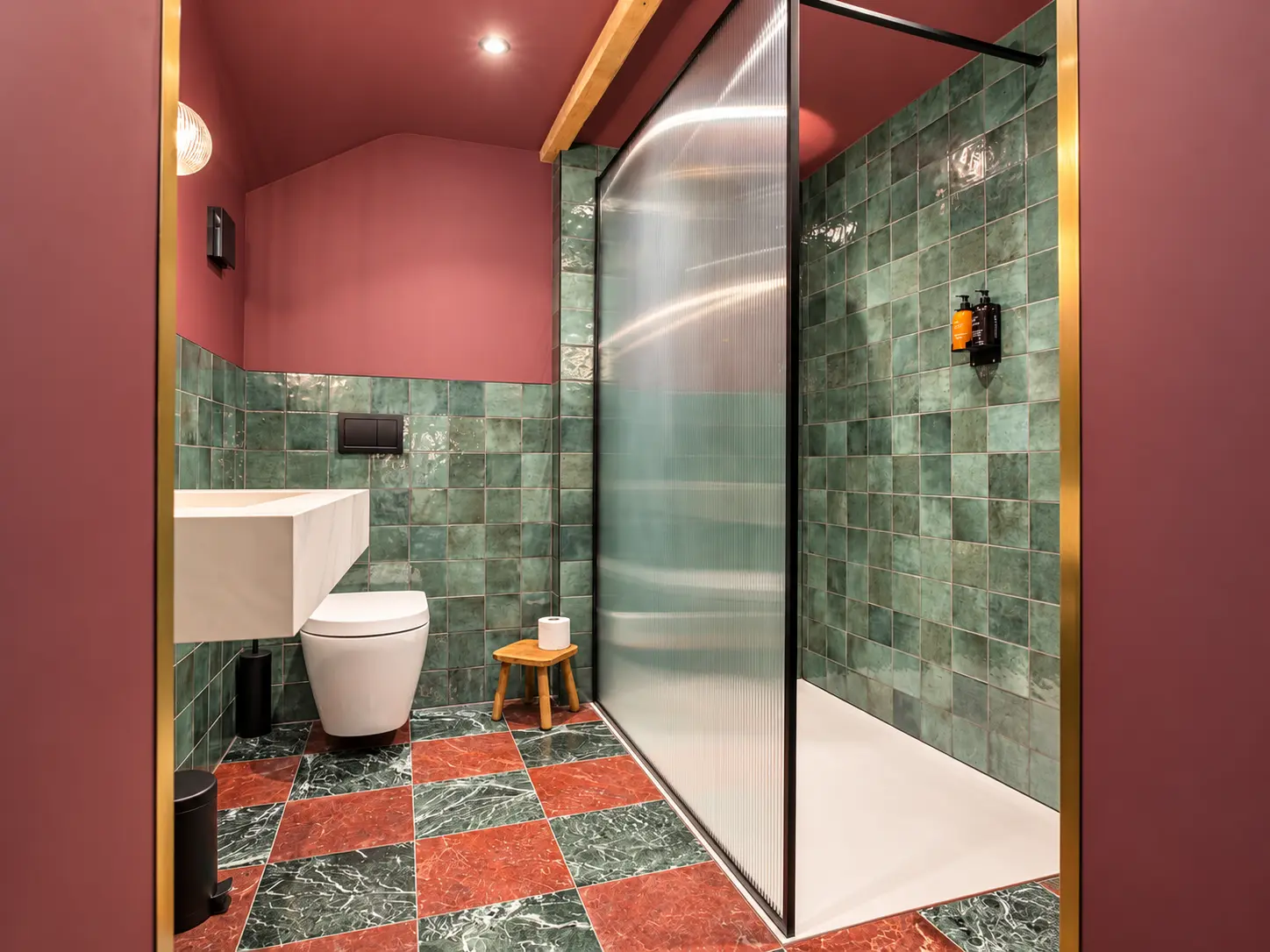 Green-tiled shower room with fluted glass, brass fittings and a patterned floor